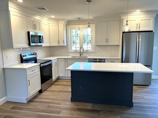 a kitchen with stainless steel appliances a sink dishwasher a refrigerator and a stove with wooden floor