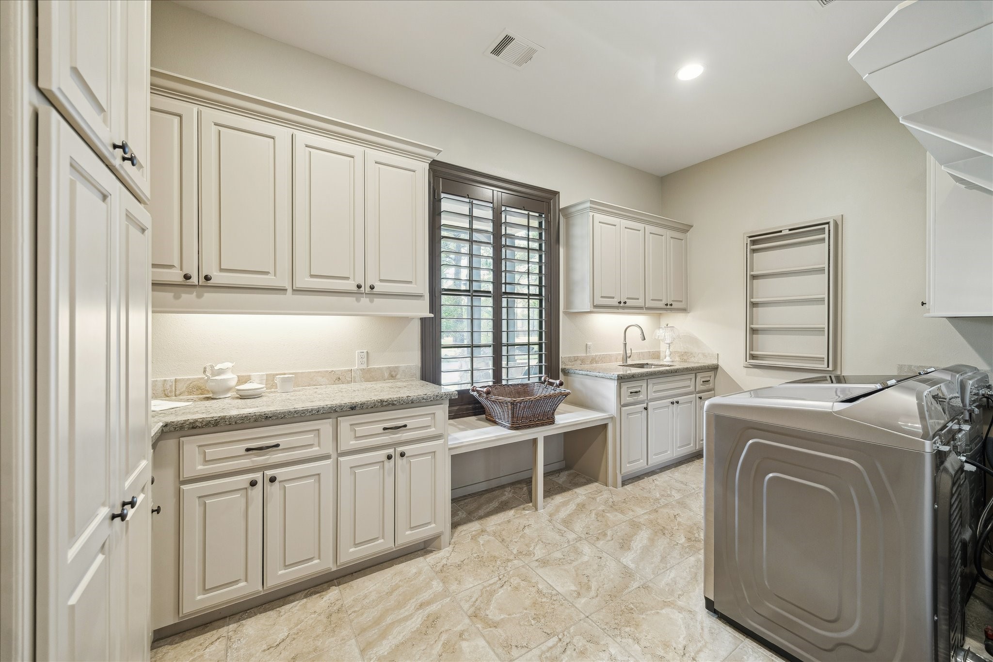 11 Willowcreek Ranch Road Tomball, TX 77377 - Photo 39 of 49 This dream laundry room may be accessed from the hallway or directly from one of the primary closets. It features generous cabinetry for maximum organization. It boasts a sink, built in ironing station, granite countertops and a window providing natural light.