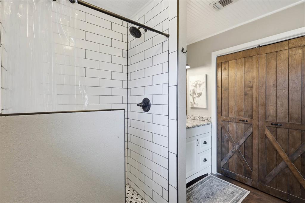 308 West 1st Street Springtown, TX 76082 - Photo 24 of 39 Shower with subway tile surround, dark bronze fixtures, and a mosaic tile floor