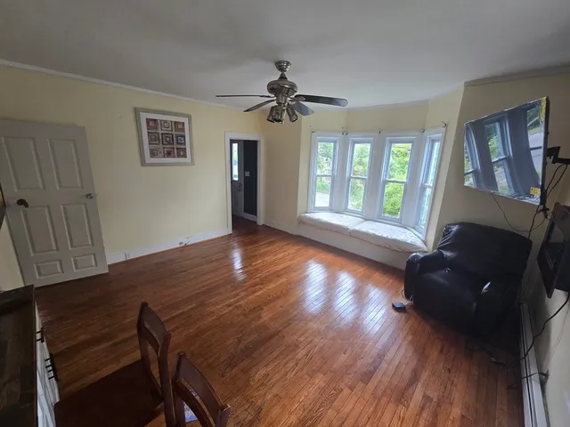 a view of a livingroom with furniture a ceiling fan and wooden floor