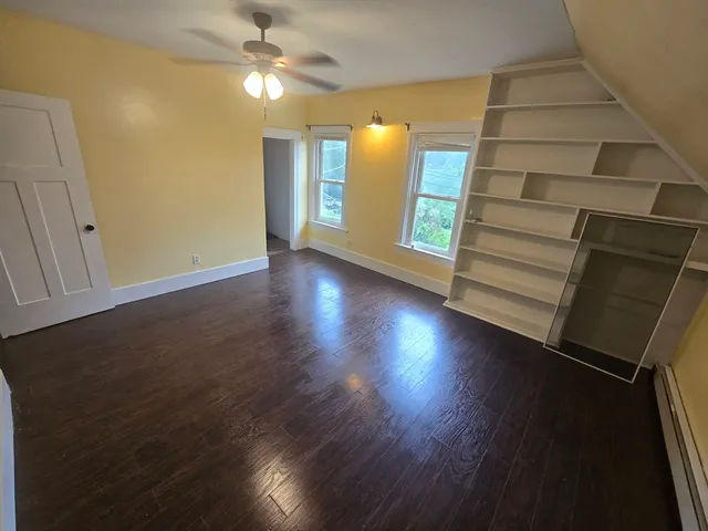 a view of an empty room with window and wooden floor