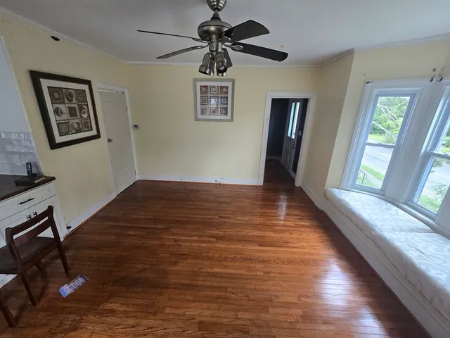 a view of an empty room with window and wooden floor