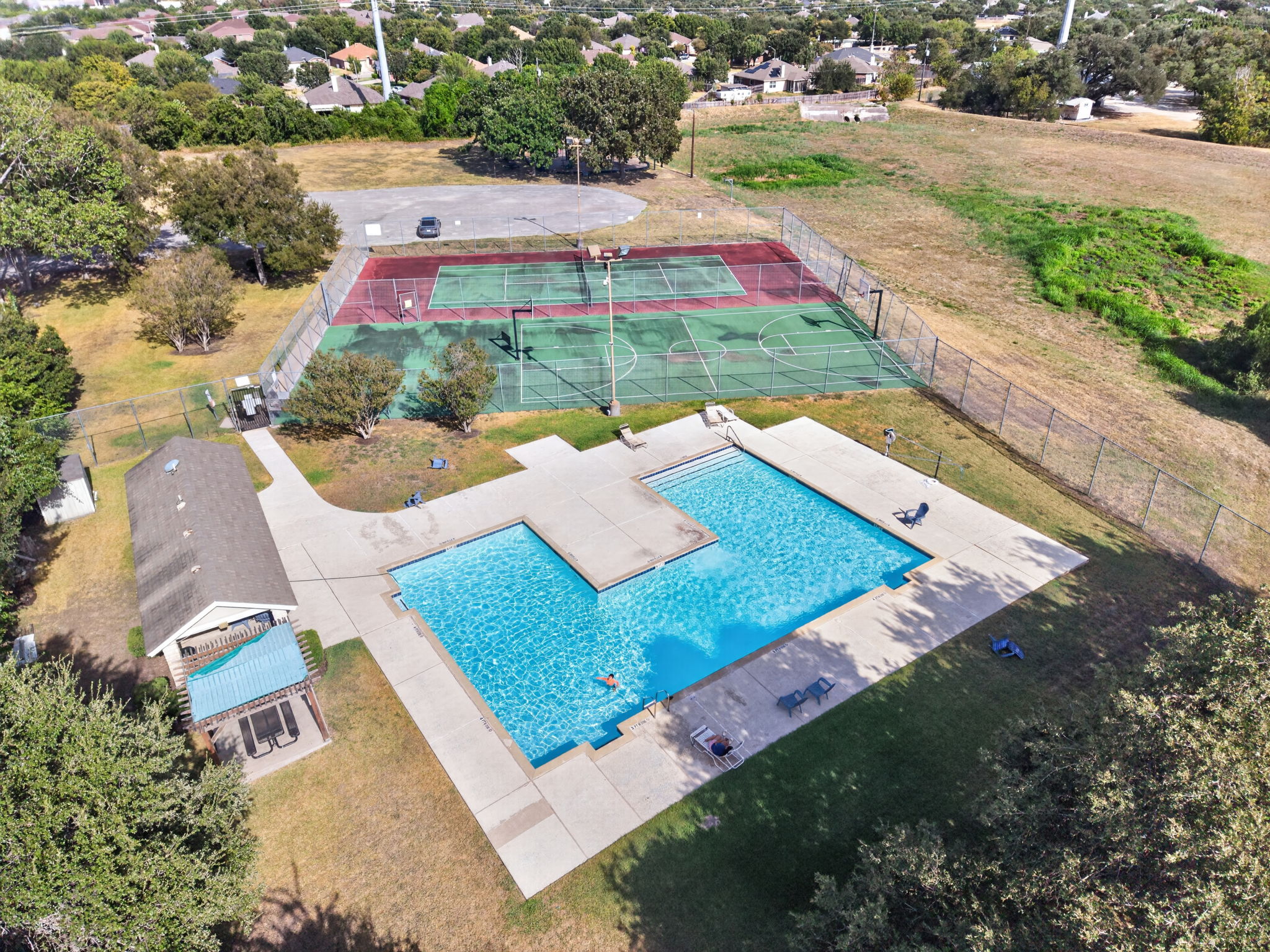806 Mountain Ridge Drive Leander, TX 78641 - Photo 37 of 40 An aerial view showcases the sparkling community swimming pool alongside sport courts and open green space.