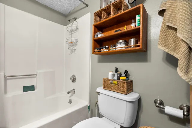 a white toilet sitting next to a bathroom sink and tub