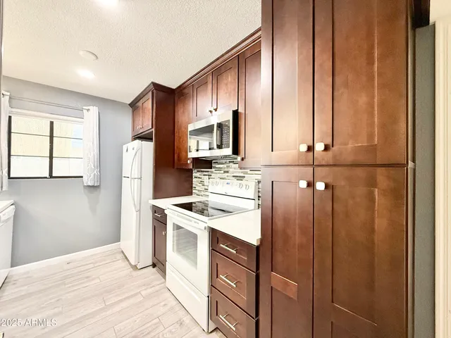 a kitchen with stainless steel appliances granite countertop a refrigerator a stove a sink and dishwasher with wooden floor