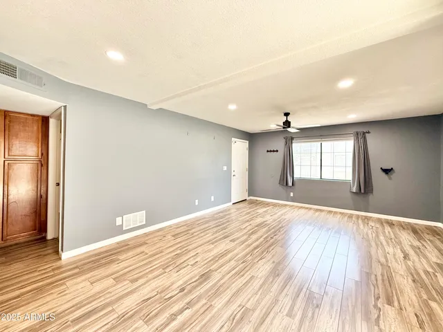 a view of an empty room with wooden floor and a window