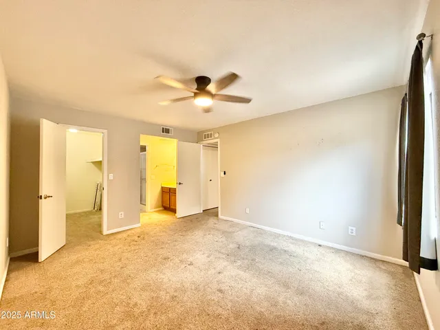 an empty room with closet and a chandelier fan