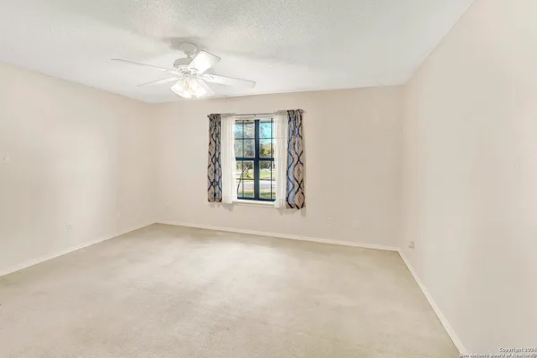 an empty room with windows and chandelier fan
