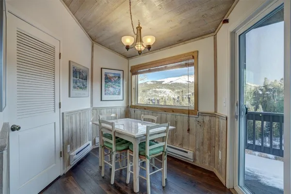 a dining room with wooden floor a chandelier a wooden table and chairs
