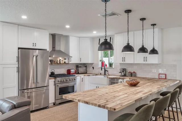 a kitchen with stainless steel appliances granite countertop a sink a stove a refrigerator and island