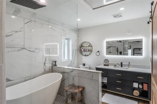 a bathroom with a tub a sink and a large mirror
