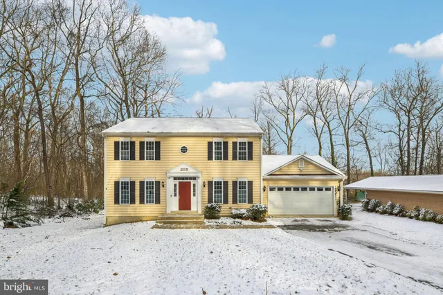 a front view of a house with a yard and covered with snow