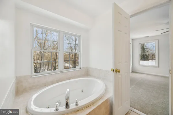a white bath tub sitting in a bathroom next to a window