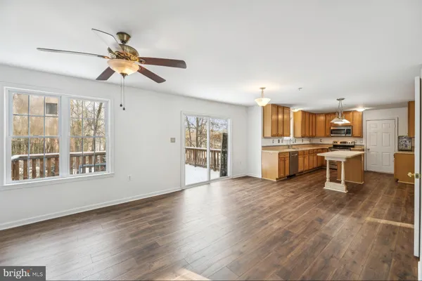 a living room with stainless steel appliances kitchen island granite countertop a stove and a refrigerator