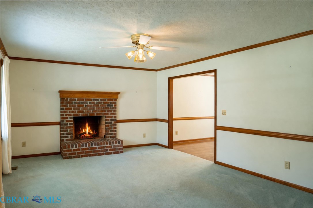 2847 Decatur Drive Hayes, VA 23072 - Photo 11 of 30 Unfurnished living room with a fireplace, crown molding, light carpet, a ceiling fan, and a textured ceiling