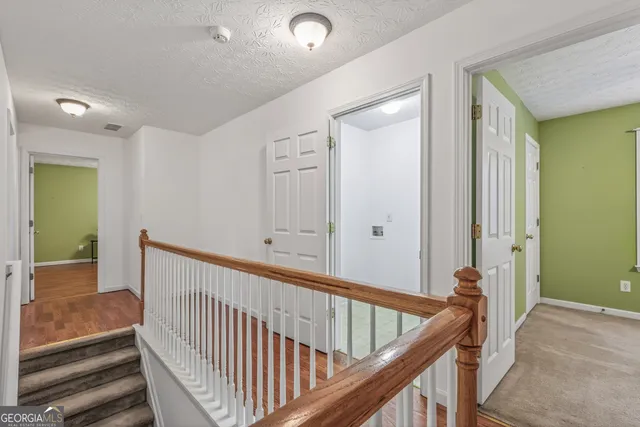 a view of a hallway with wooden staircase and stairs