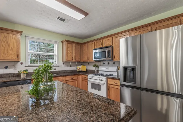 a kitchen with stainless steel appliances granite countertop a refrigerator sink stove microwave and cabinets