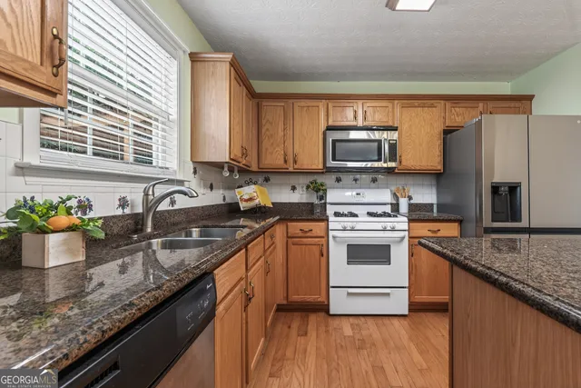 a kitchen with stainless steel appliances granite countertop a sink stove and refrigerator
