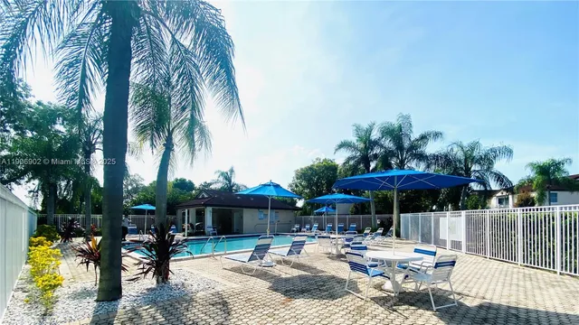 a patio with a table and chairs under an umbrella with a fire pit