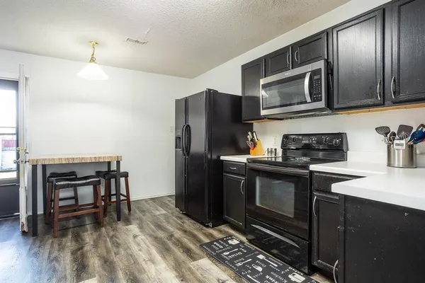 a kitchen with stainless steel appliances granite countertop a refrigerator microwave and wooden floor