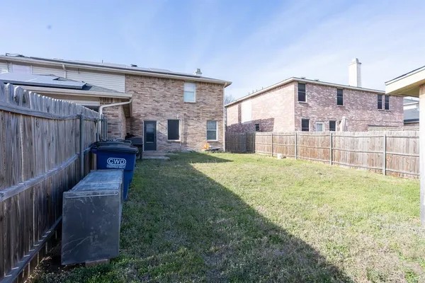 a view of a backyard with couches plants and wooden fence