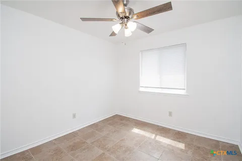 an empty room with a chandelier fan and windows