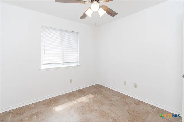an empty room with a window and a fan