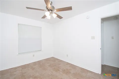 an empty room with a fan & a window