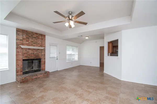 an empty room with windows fireplace and fan