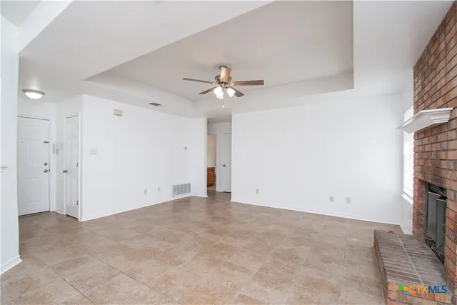 an empty room with fireplace and ceiling fan