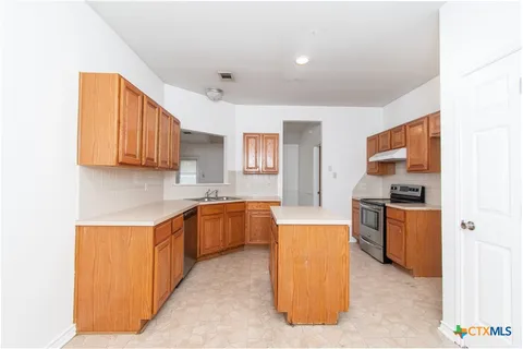 a kitchen with stainless steel appliances granite countertop a stove top oven a sink dishwasher and a refrigerator with wooden floor