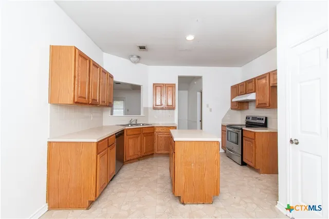 a kitchen with stainless steel appliances granite countertop a stove top oven a sink dishwasher and a refrigerator with wooden floor