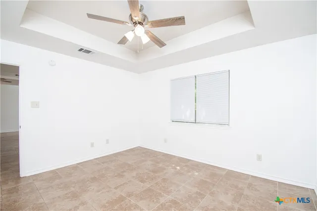 an empty room with a window and a ceiling fan
