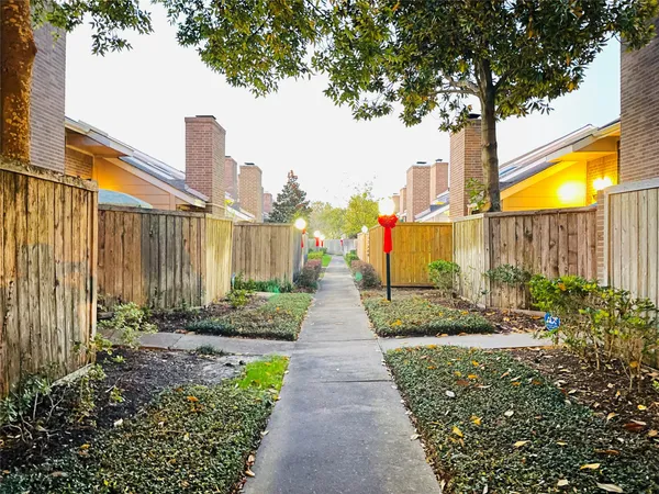 a pathway of a house with a yard and table and chairs