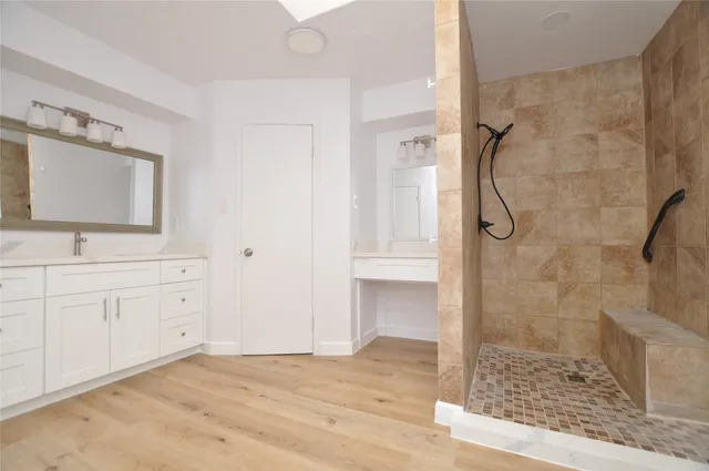a bathroom with a granite countertop sink a mirror and shower