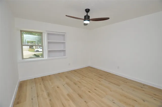 a view of empty room with wooden floor and fan