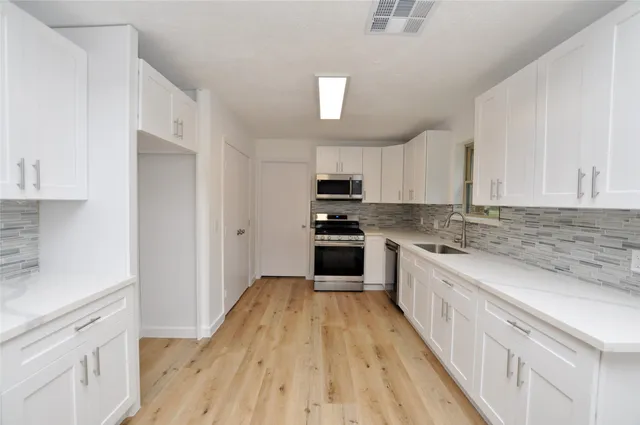 a kitchen with granite countertop a sink cabinets stainless steel appliances and a counter space
