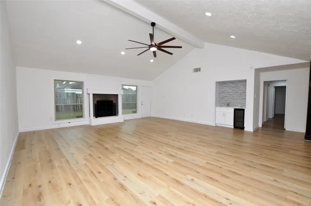 an empty room with wooden floor fireplace and windows