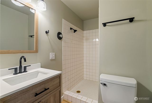 a bathroom with a sink a toilet a mirror and shower