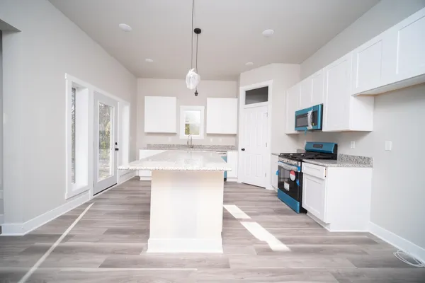 a large kitchen with granite countertop a stove top oven a sink dishwasher and a refrigerator with wooden floor