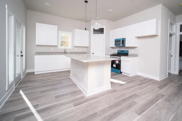a kitchen with stainless steel appliances granite countertop a white cabinets and a wooden floor
