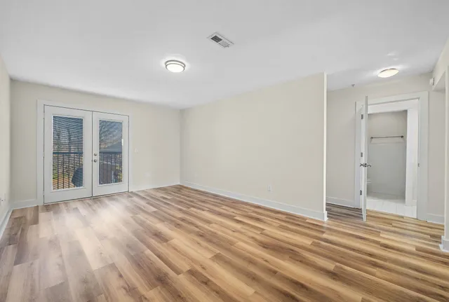 a view of an empty room with wooden floor and a window