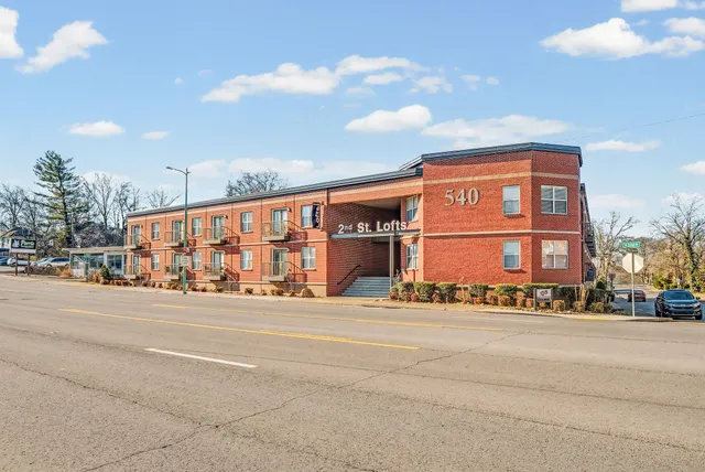 a front view of multi story residential apartment building with yard and traffic signal