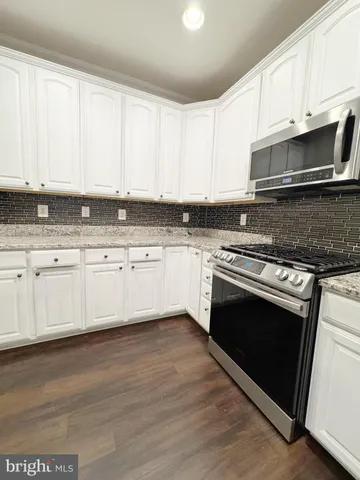 a kitchen with granite countertop white cabinets and appliances