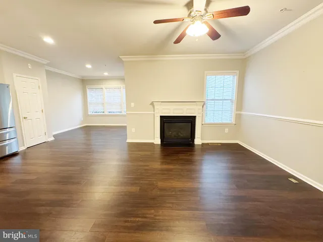 an empty room with wooden floor fireplace and windows