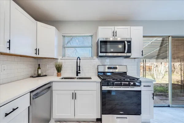 a kitchen with granite countertop a stove a sink and a microwave