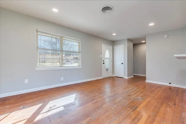 a view of an empty room with wooden floor and a window