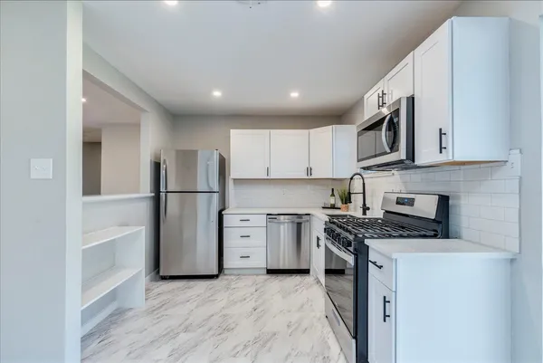 a kitchen with stainless steel appliances granite countertop a stove a refrigerator and a microwave