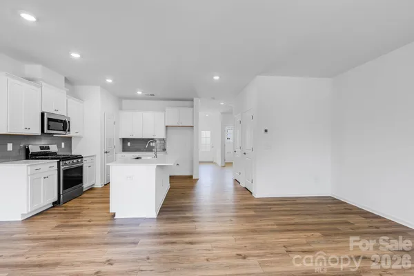 a view of kitchen with microwave stove refrigerator and cabinets