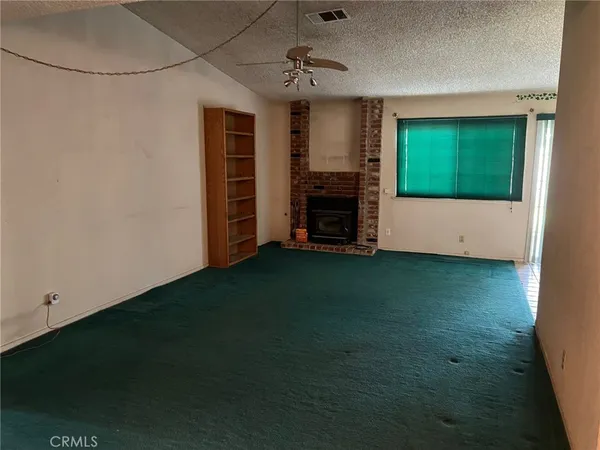 a view of an empty room with a fireplace and a window